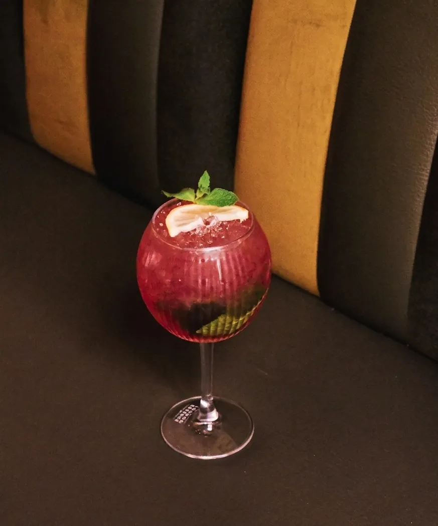 Cocktail rouge servi sur banquette de velours
